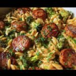 A close-up of Chicken Sausage Broccoli Orzo, featuring browned sausage, green broccoli, and orzo pasta, garnished with parsley.