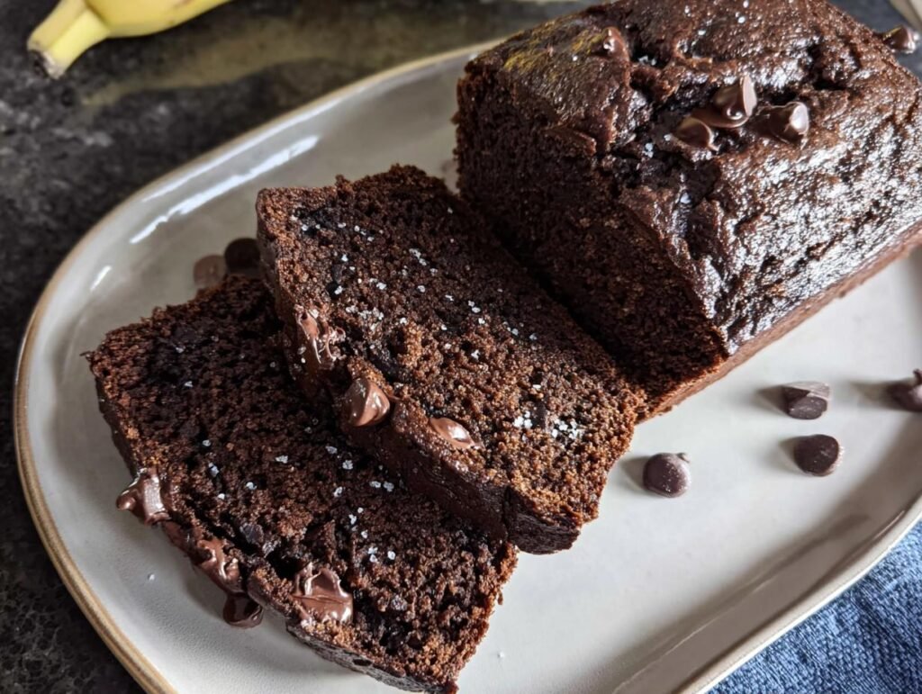 Slices of rich Chocolate Espresso Banana Bread on a plate, topped with chocolate chips and sea salt.