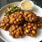 A plate of golden Crispy Vegan Chickpeas served with a side salad and dipping sauce.