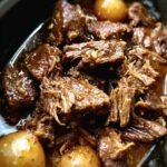 Close-up of tender Crockpot Garlic Butter Beef roast with potatoes in a rich, savory sauce.