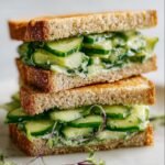 Two stacked cucumber salad sandwiches on toasted bread, filled with creamy cucumber salad.