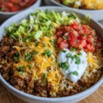 Close-up of an Easy Taco Rice Bowl with ground beef, rice, lettuce, cheese, salsa, and sour cream.