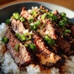 Close-up of Korean BBQ Steak Rice bowl topped with green onions and sesame seeds.