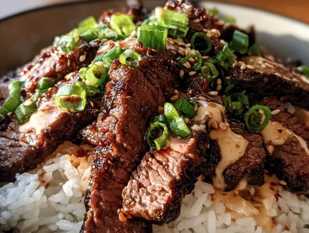 Close-up of a Korean BBQ Steak Rice bowl, featuring sliced steak, rice, green onions, and sesame seeds.