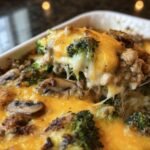 Close-up of a cheesy low-carb oven dish featuring broccoli, mushrooms, and a melted cheese topping.