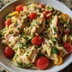 Close-up of Protein Chicken Orzo salad with grilled chicken, orzo pasta, cherry tomatoes, and fresh herbs.