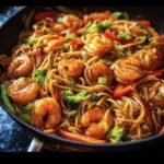Close up of Shrimp Stir with Noodles, featuring shrimp, noodles, broccoli, and red peppers in a pan.