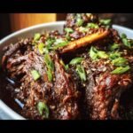 Close-up of Slow Roast Asian Beef, garnished with sesame seeds and green onions in a bowl.