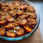 Close-up of a Sweet Potato & Feta Crumble in a glass baking dish, topped with golden crumble and fresh herbs.
