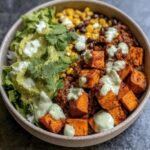 Overhead shot of a Sweet Potato Taco Bowl with sweet potatoes, corn, beans, guacamole, and lettuce.
