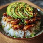 A delicious bowl of Teriyaki Chicken Avocado Rice, topped with sesame seeds and green onions.