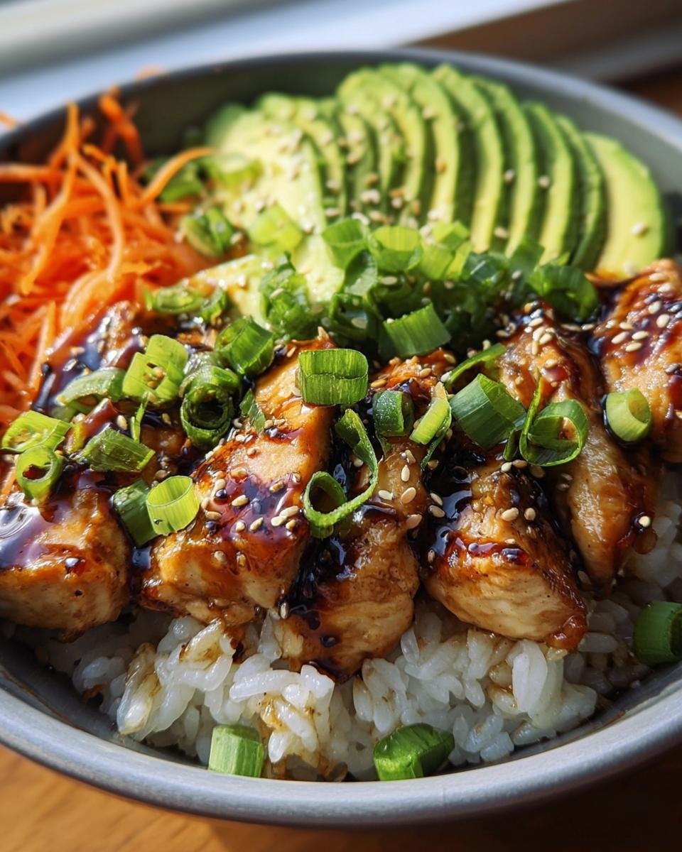 A delicious Teriyaki Chicken Avocado Rice Bowl with rice, chicken, avocado, carrots, and green onions.