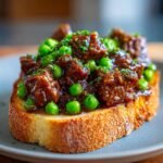 Open-faced Best Beef Manhattan sandwich with peas and parsley on toasted bread.
