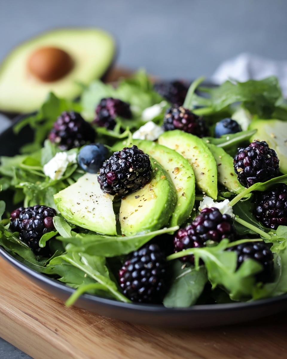 A close-up of Blackberry, Avocado & Arugula Salad with fresh blackberries, avocado slices, and arugula.