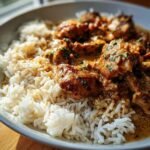 A bowl of Chicken and Rice, featuring tender chicken pieces in a creamy sauce served over fluffy white rice.