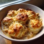 A bowl of Chicken & Biscuit Dinner Cobbler, featuring golden biscuits over a creamy chicken filling.