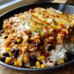 A flavorful Chicken Enchilada Bowl with rice, corn, black beans, chicken, cheese, and enchilada sauce.