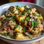 Bowl of creamy Chicken Normandy with potatoes, mushrooms, bacon, and parsley garnish.