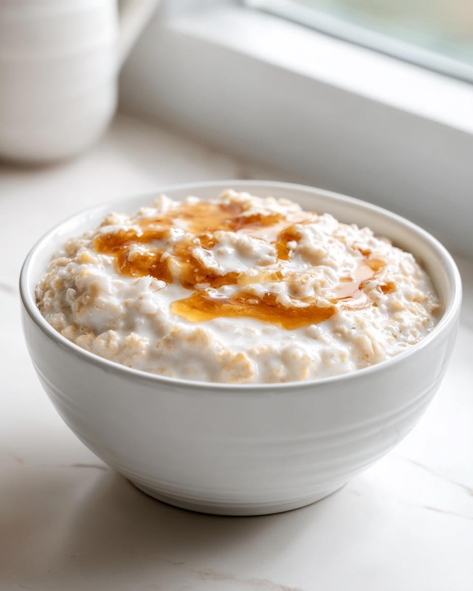 A bowl of creamy Coconut Cream Oats topped with a drizzle of syrup, ready to eat.