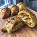 Golden Crab Crescent Bites Delight on a wooden board, one cut open to show the crab filling.