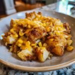 A serving of crispy cheddar corn potato dish on a plate, featuring golden potatoes and melted cheese.