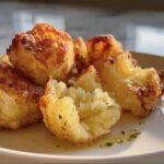 Close-up of golden Crispy Mashed Potato bites on a white plate, showcasing their crispy exterior and soft interior.
