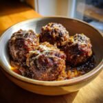 A bowl of delicious French Onion Meatballs topped with melted cheese and caramelized onions.