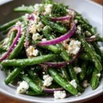 Close-up of Green Bean and Feta Salad with red onions and dill, served in a white bowl.