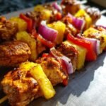 Close-up of Hawaiian Chicken Pineapple Kebabs with chicken, pineapple, red pepper, and red onion on a skewer.