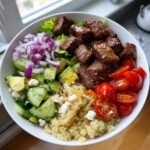 Overhead shot of a vibrant Healthy Steak Bowl with steak, quinoa, avocado, cucumber, tomatoes, and red onion.