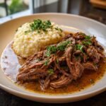 A plate of Italian Pot Roast & Parmesan Risotto, garnished with fresh parsley.