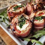 Close-up of Italian Sushi rolls wrapped in prosciutto, drizzled with balsamic glaze, and garnished with arugula.