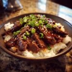 A delicious bowl of Korean BBQ Steak Rice topped with green onions and sesame seeds.