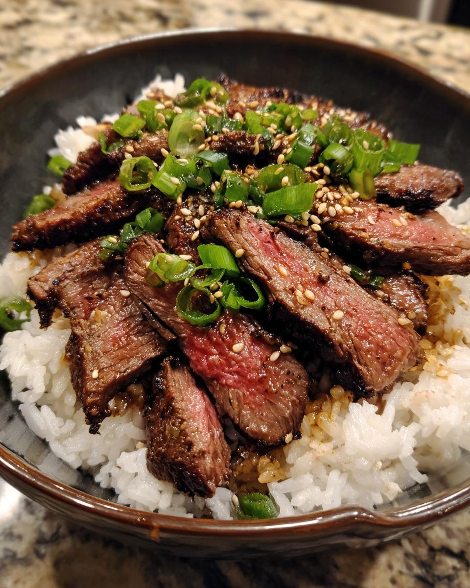 A delicious bowl of Korean BBQ Steak Rice, garnished with sesame seeds and chopped green onions.