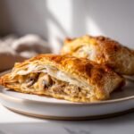 Close-up of a flaky Mushroom & Gruyère Puff Pastry, cut open to show the savory filling.