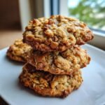 A stack of three Protein Greek Yogurt Cookie on a white plate, showcasing their texture and ingredients.