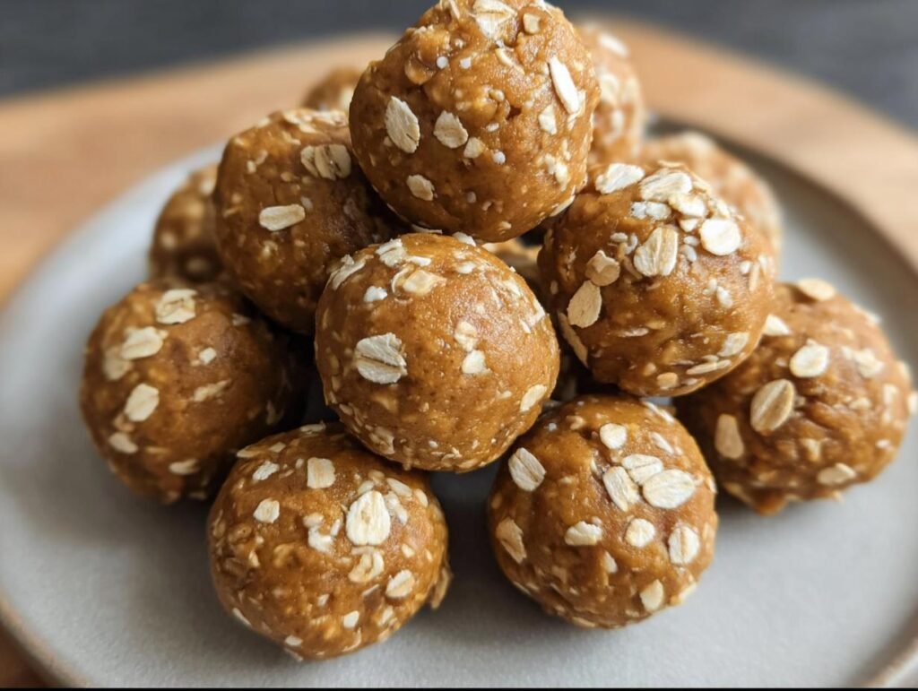 A stack of homemade Pumpkin Protein Balls, rolled in oats, on a plate. Healthy snack idea.