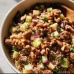 A vibrant bowl of Quinoa Apple Salad with quinoa, apples, walnuts, and red onion.
