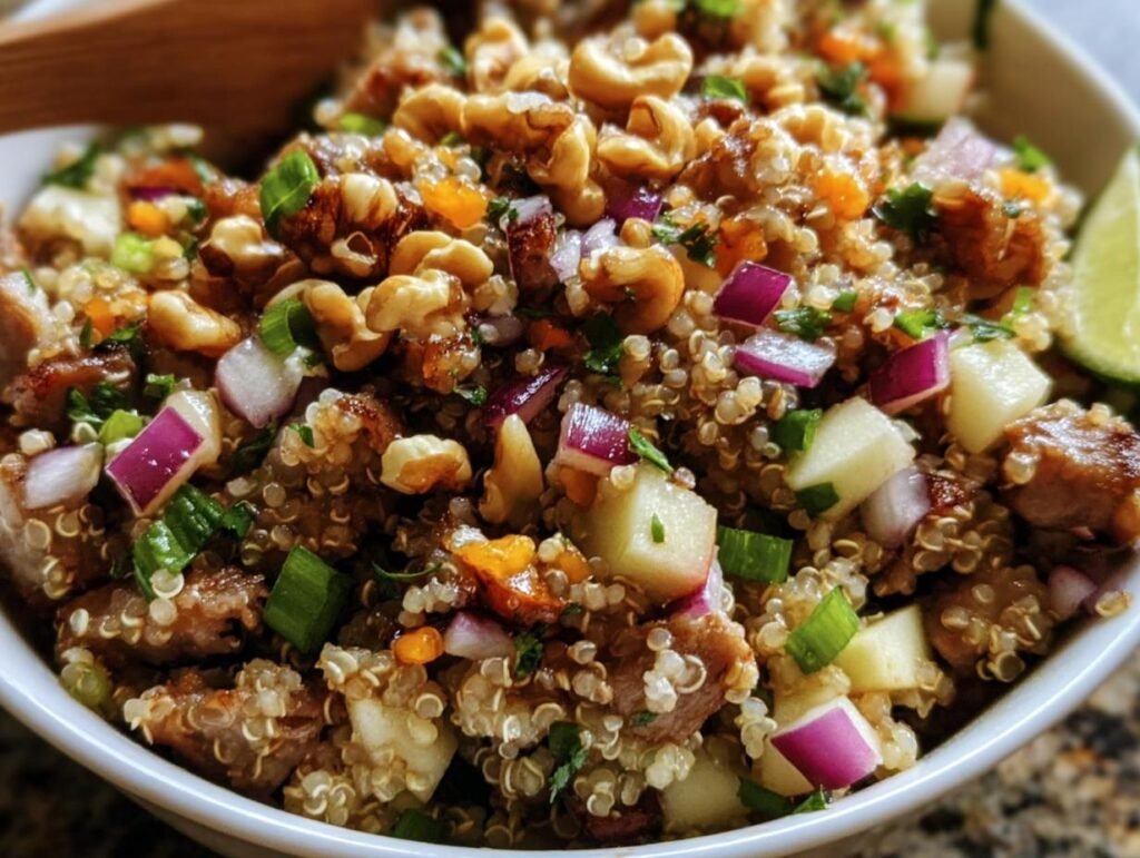 Close-up of a vibrant Quinoa Apple Salad with quinoa, apples, red onion, nuts, and herbs in a white bowl.