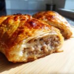 Close-up of a sliced Savory French Onion Sausage Roll, showcasing the flaky pastry and flavorful filling.