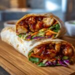 Two Sweet Chili Chicken Wraps, one cut in half to show the chicken and vegetable filling.