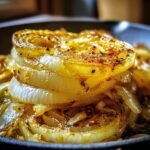 Close-up of a stack of golden-brown cooked Tennessee Onions rings on a plate.