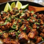 A bowl of zesty ginger lime pork with rice, garnished with fresh cilantro and lime wedges.