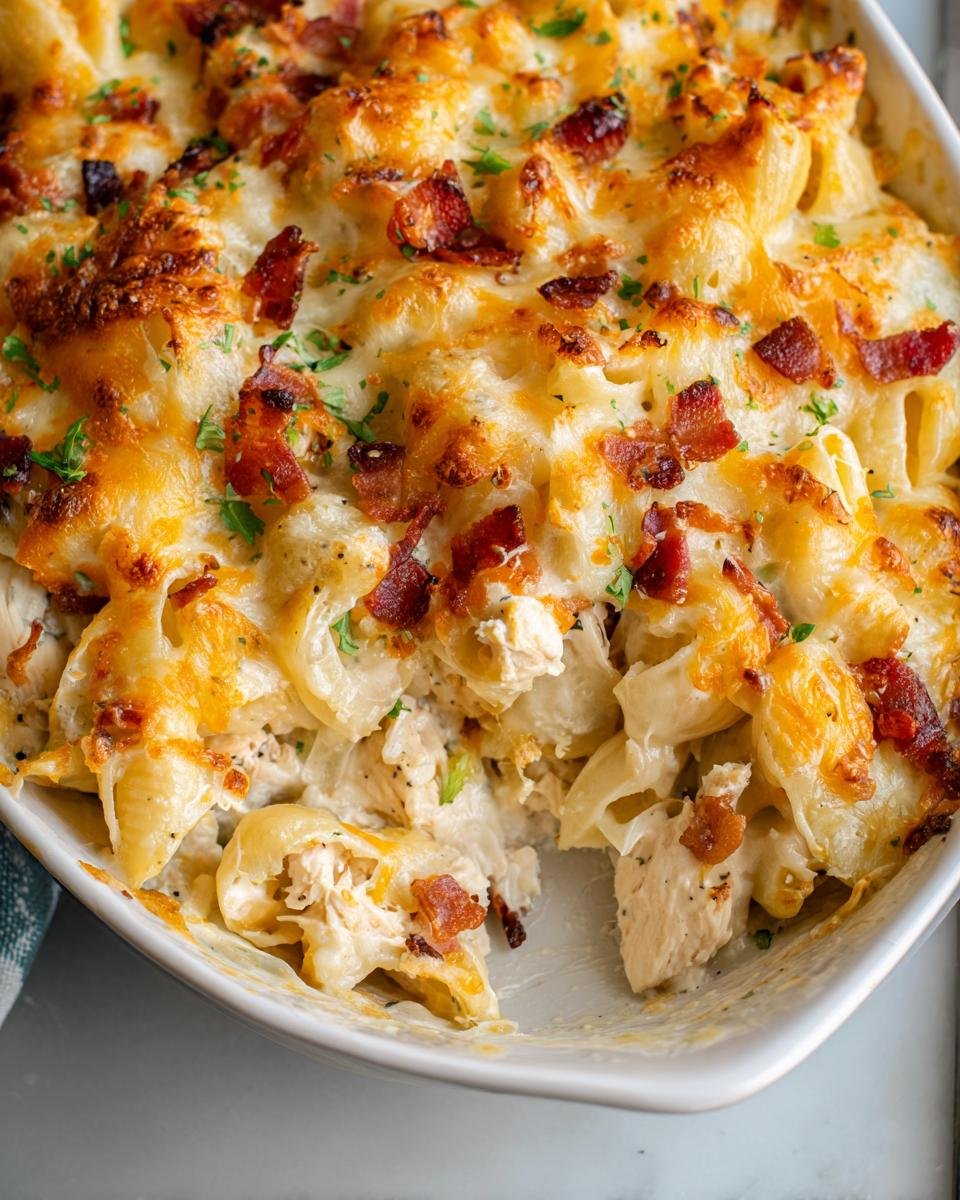 Close-up of a scoop taken out of an Irresistible Crack Chicken Casserole topped with melted cheese and bacon.