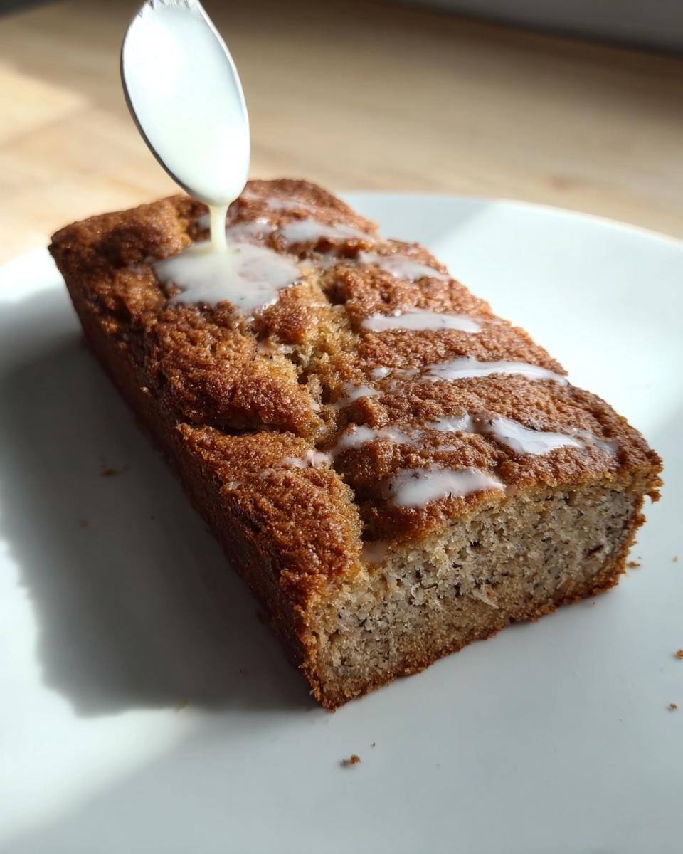 A slice of moist banana bread from the best banana bread recipe with ripe bananas, drizzled with glaze.