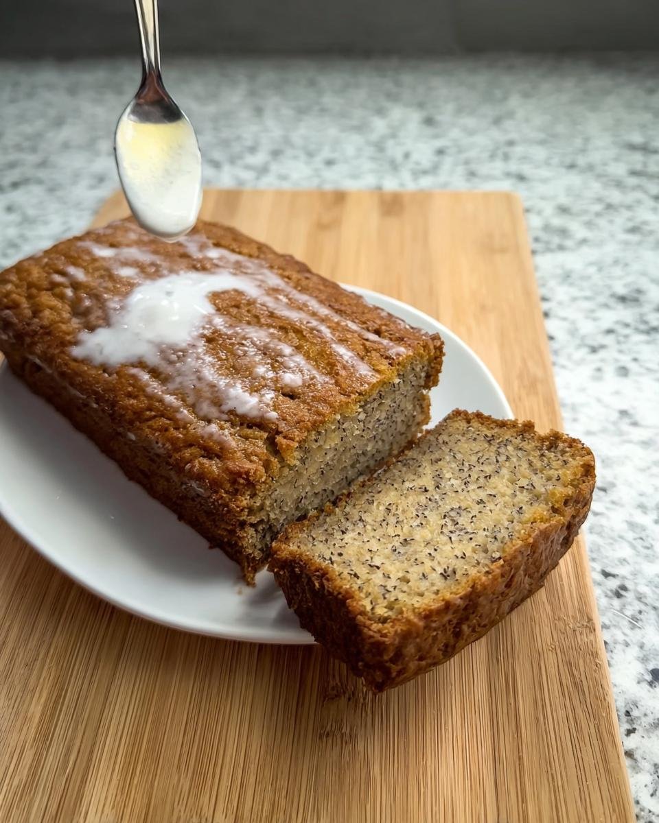 A slice of moist banana bread with ripe bananas, drizzled with icing.