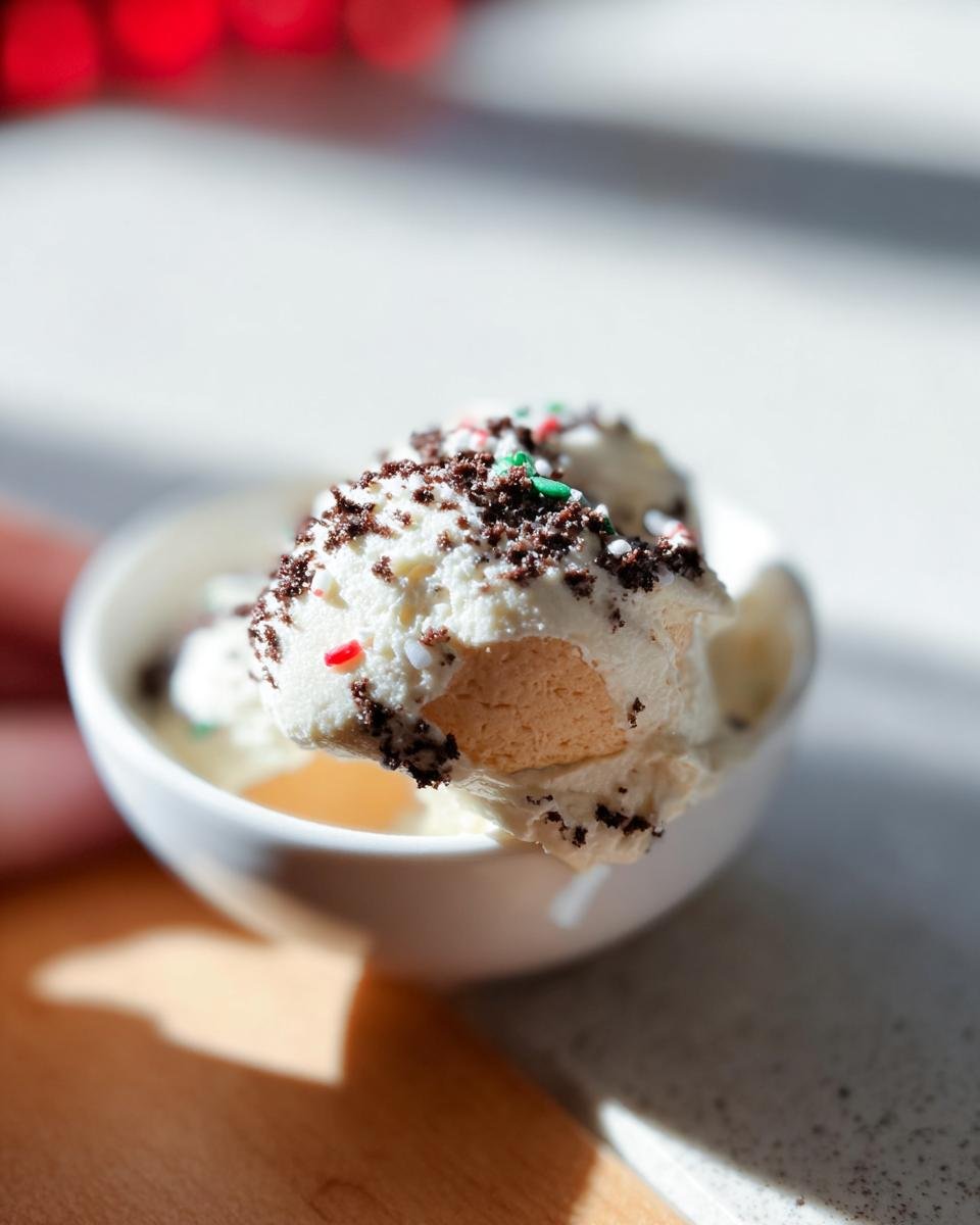 A close-up of a bowl of creamy ice cream topped with chocolate cookie crumbs, festive sprinkles, and a piece of cake, perfect for a Little Debbie Cake Dip Recipe.