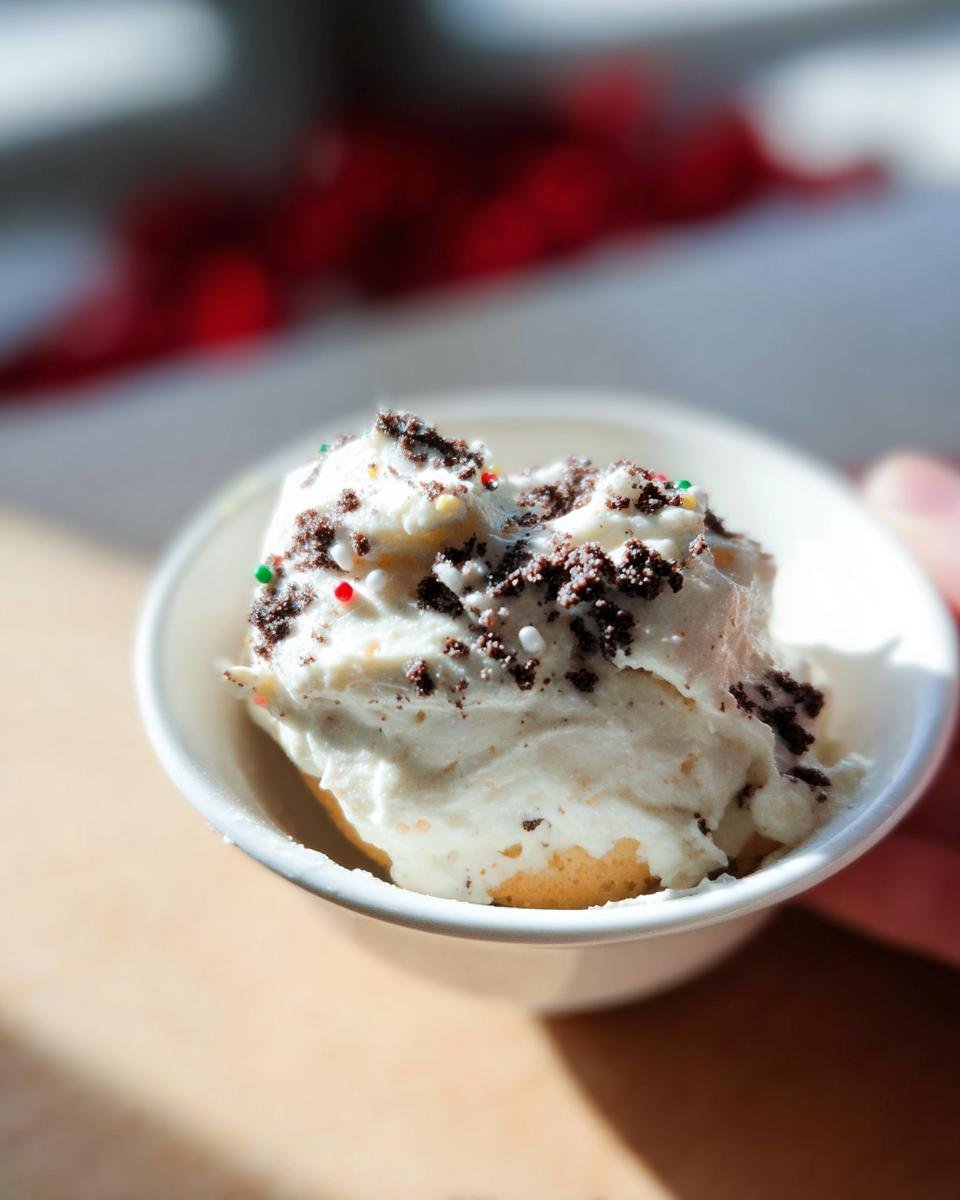 A close-up of a serving of Little Debbie Cake Dip Recipe, topped with cookie crumbs and colorful sprinkles.