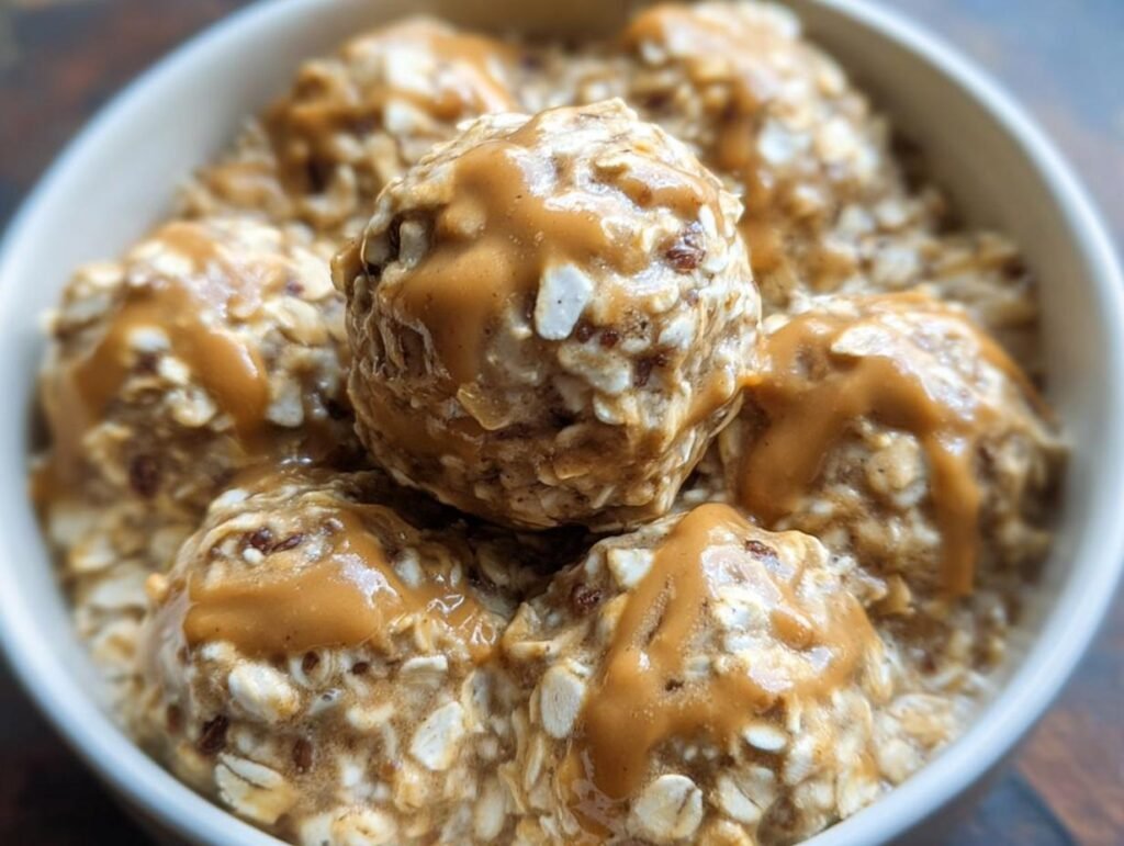 Close-up of Peanut Butter Oatmeal Energy Breakfast balls drizzled with peanut butter in a white bowl.